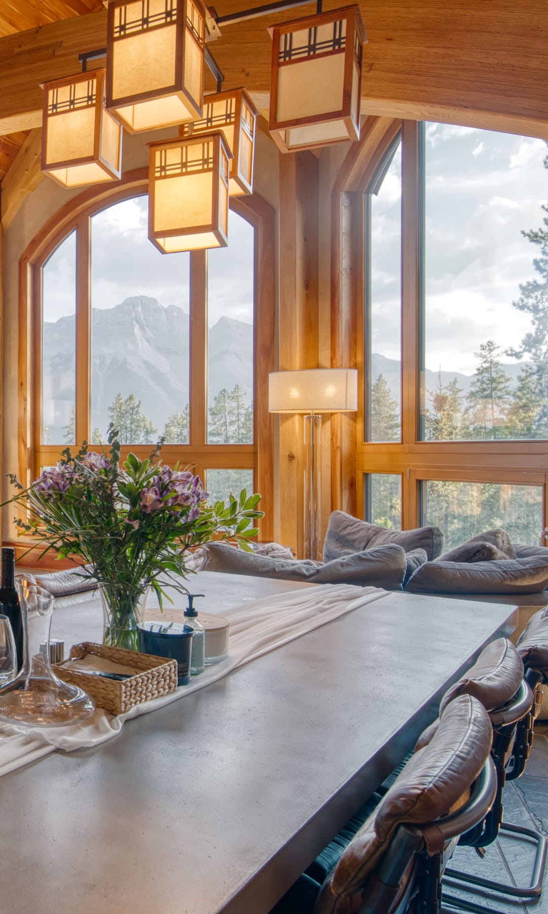 Dining room at 821 Silvertip Heights with lantern pendants beneath arched windows framing the mountains
