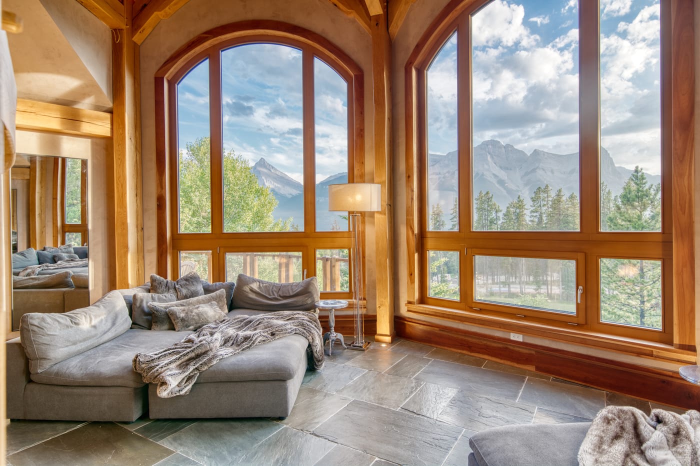 Great room at 821 Silvertip Heights with plush seating beneath soaring arched windows onto the mountains